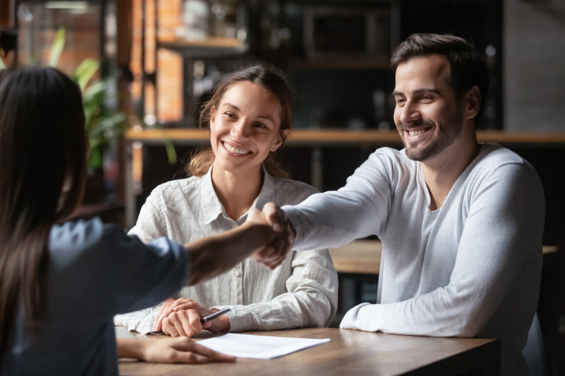 Young couple shaking hands with mortgage broker.